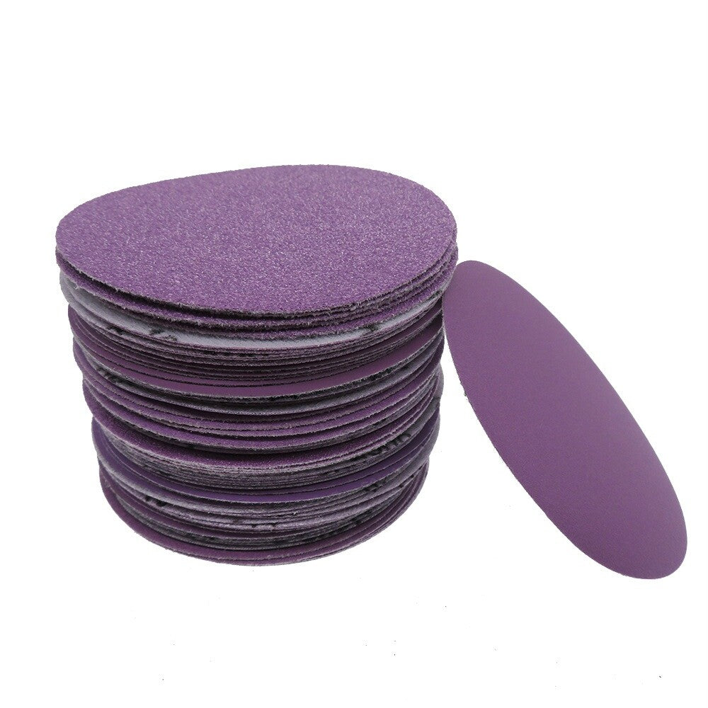 Flat-lay composition of multiple 100mm purple sandpaper discs, displaying the full product set and their uniform purple color.
