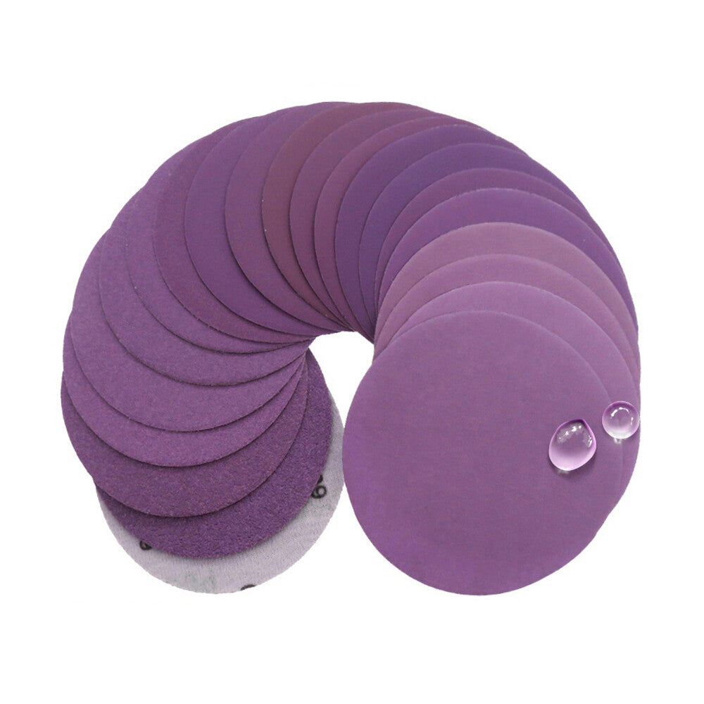 Stack of purple wet and dry sanding discs, showing their waterproof backing and uniform 100mm diameter.