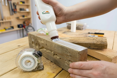 Applying wood glue evenly on timber surface using a DIY toothbrush bottle dispenser
