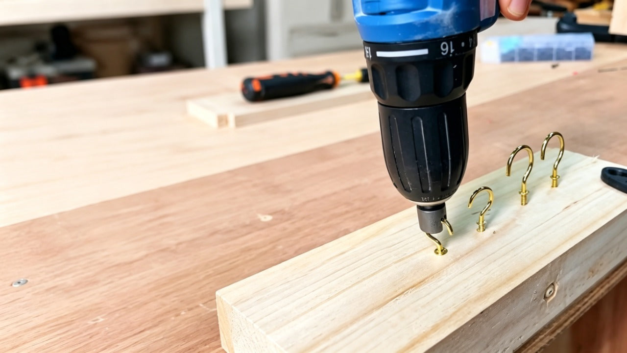 grey modified hex socket with slot mounted on black drill positioned next to wooden board with golden screw hooks installed